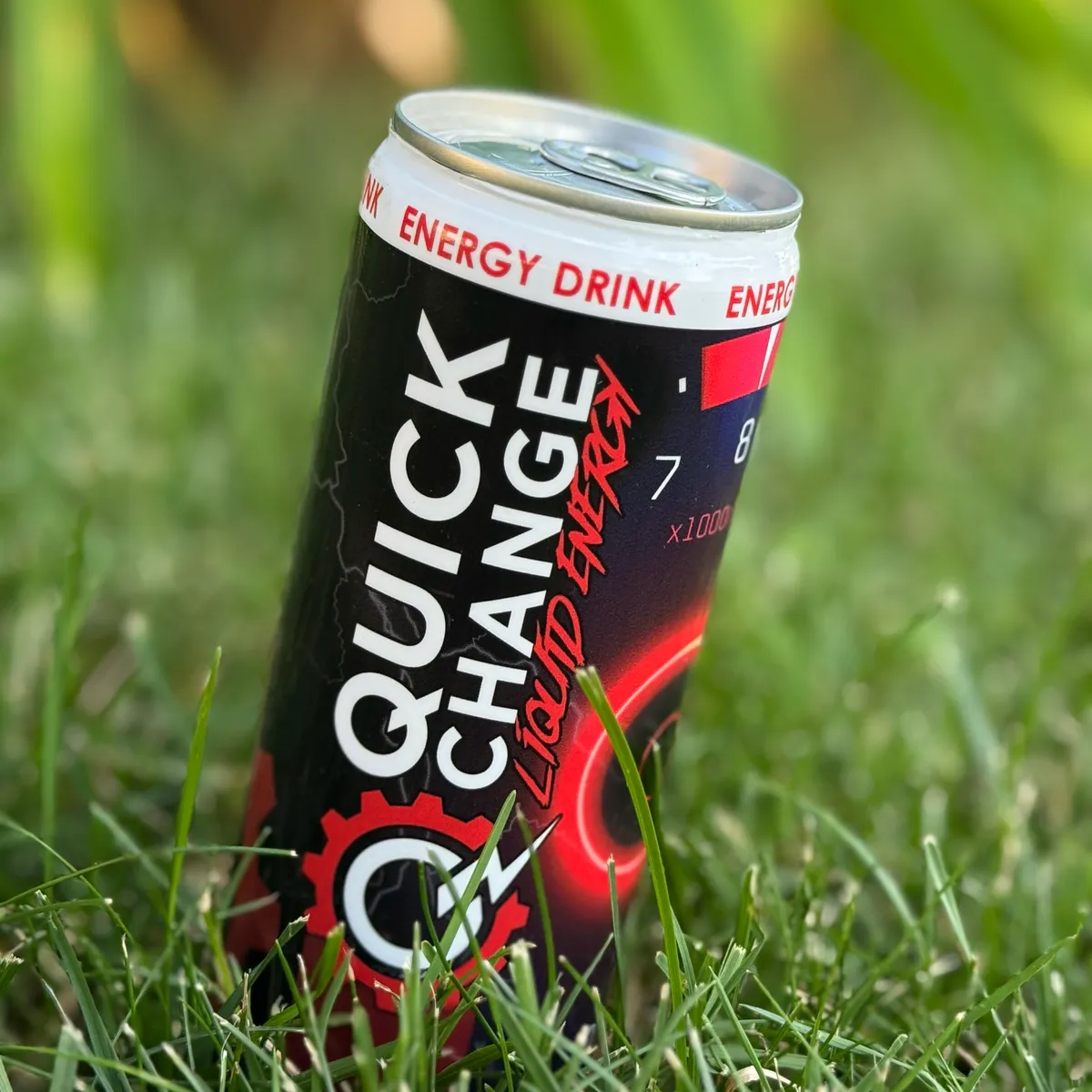 A red Quick Change Liquid Energy can standing in green grass